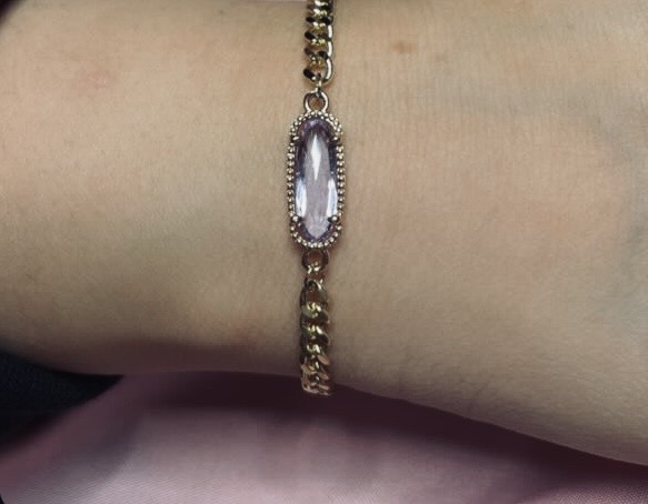 Gold chain bracelet with pink stone centerpiece