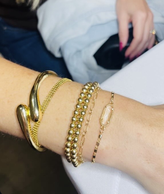 Stacked gold beaded and chain bracelets