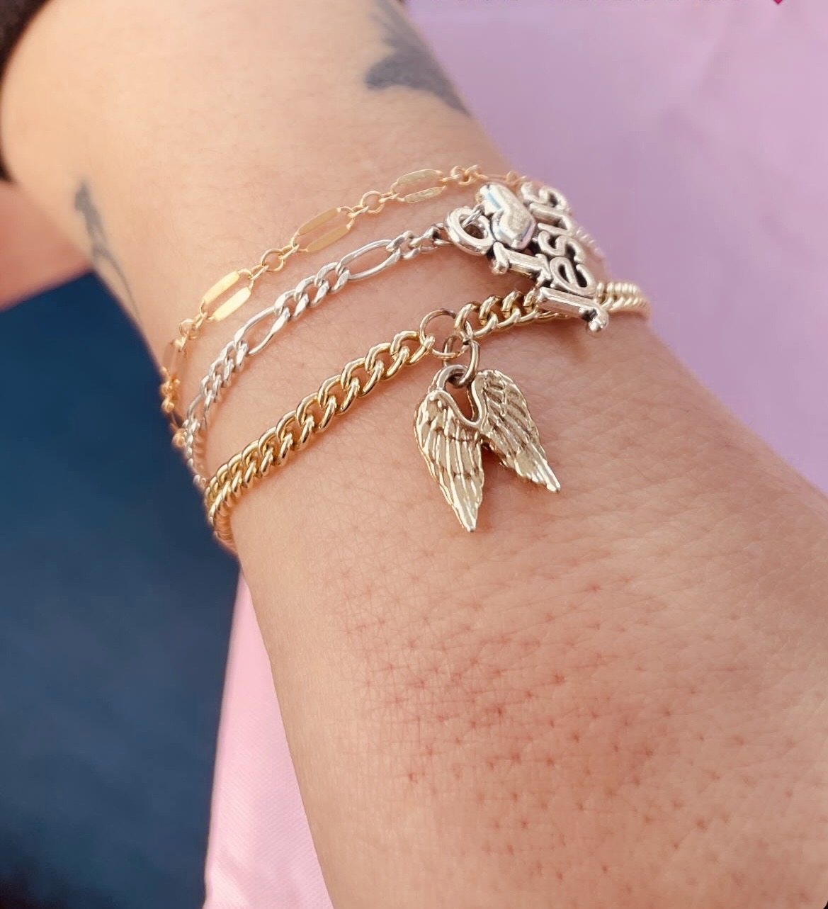 Layered gold and silver bracelets with angel wing charms