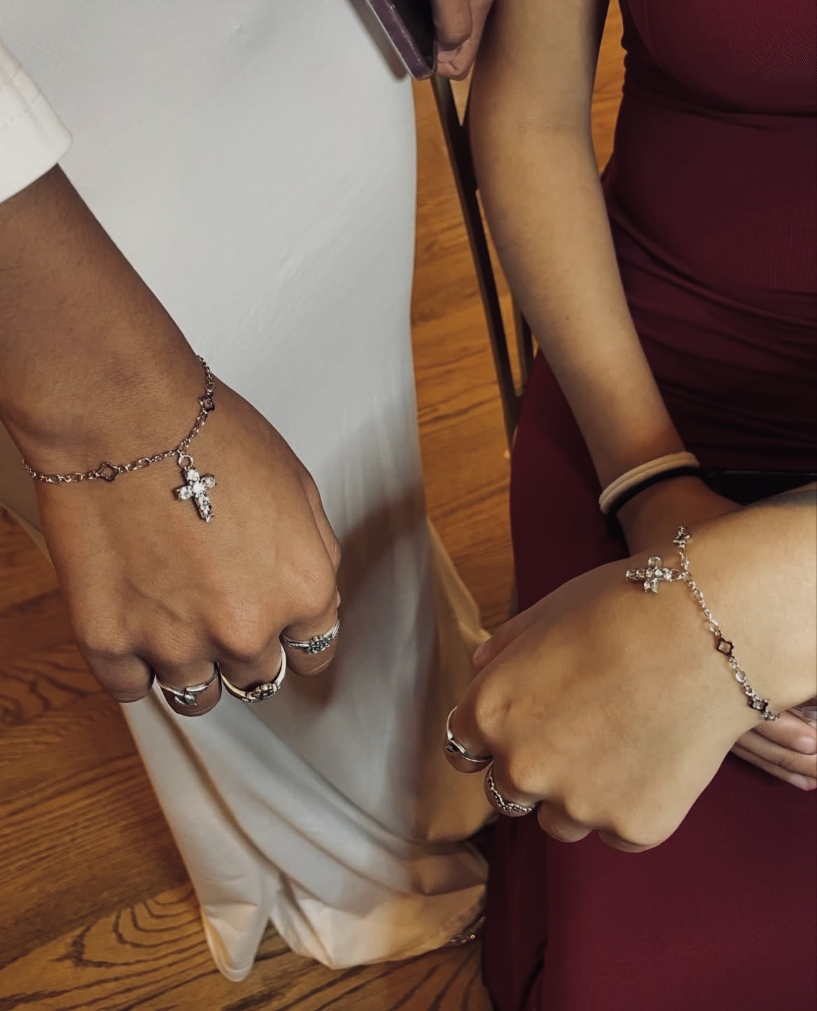 Matching silver cross charm bracelets on two wrists